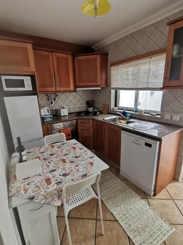 a kitchen with a table with chairs and a refrigerator at Studio acolhedor e confortável - Nazaré Waves in Nazaré