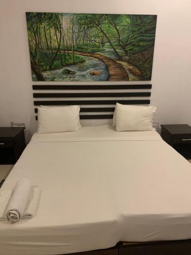 ein Schlafzimmer mit einem weißen Bett und einem Gemälde an der Wand in der Unterkunft Sunrise Palace Negombo in Negombo