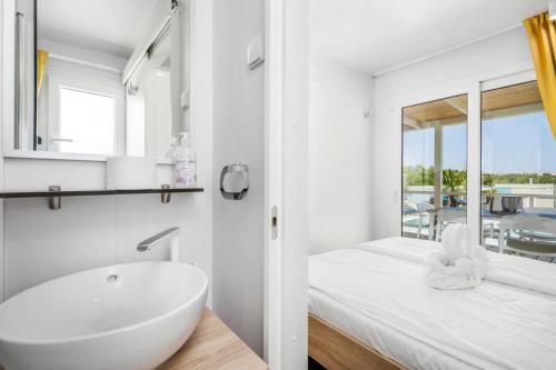 ein weißes Badezimmer mit einer Badewanne und einem Waschbecken in der Unterkunft Mobile Homes in Camping Omisalj, island Krk, with swimmingpool in Omišalj