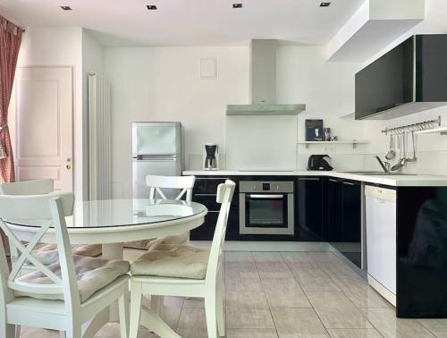 una cocina blanca con mesa y sillas. en Maison de ville confortable avec piscine, en Pons