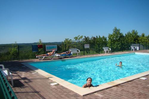 Dos personas están nadando en una piscina en CAMPING LES GRAVES - Cabane TITHOME, en Saint-Pierre-Lafeuille