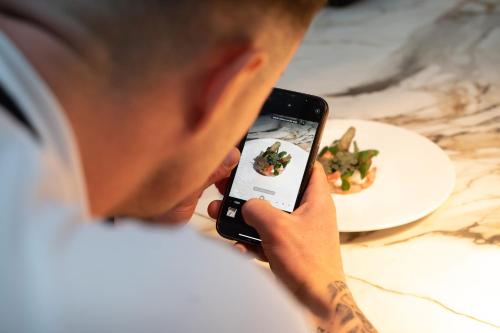 a man taking a picture of a plate of food at Hotel Ter Zand - Handwritten Collection in Burgh Haamstede