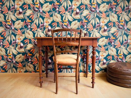 a wooden table and a chair with a floral wallpaper at Chambre D'hôtes Francine et Gérard in Le Mans