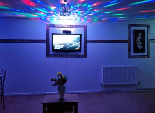 a room with a television and a vase of flowers on a table at *F1*5GH* Setup for your most relaxed & amazing stay + Free Parking + Free Fast WiFi * in Leeds