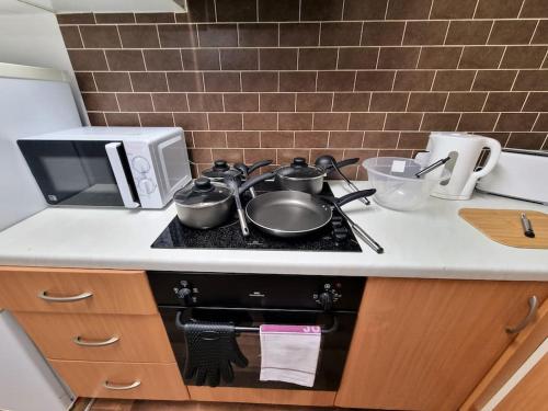 a kitchen with a stove with pots and pans on it at *F1*5GH* Setup for your most relaxed & amazing stay + Free Parking + Free Fast WiFi * in Leeds