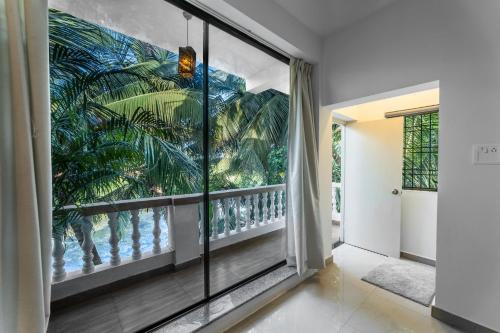 a room with a balcony with a mural of palm trees at Morii homes River view # Siolim 