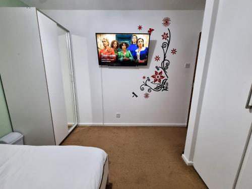 a room with a tv on a wall with a bed at *F1*5GH* Setup for your most relaxed & amazing stay + Free Parking + Free Fast WiFi * in Leeds