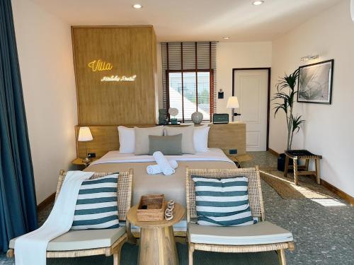 une chambre d'hôtel avec un lit et deux chaises dans l'établissement Rimtalay Resort Koh Larn, à Ko Larn