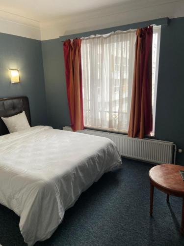 a bedroom with a bed and a window and a table at Hotel Windsor in Brussels