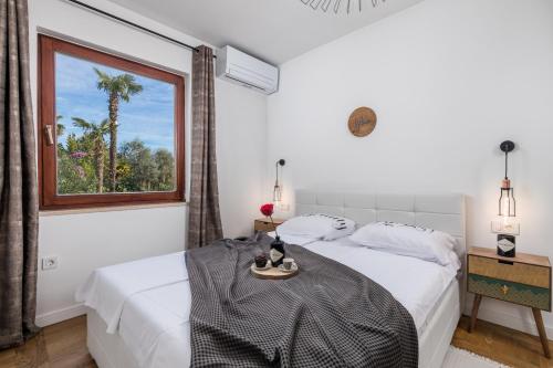 a white bedroom with a large window and a bed at Apartment Mak in Opatija