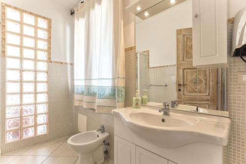 La salle de bains blanche est pourvue d'un lavabo et de toilettes. dans l'établissement Villa Janas Luxury Villa surrounded by large park, swimming pool, parking and Wifi, à Alghero