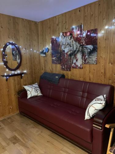 a living room with a brown leather couch and paintings at Camping Chalets Spas Pignons Rouges in Saint Romain