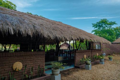 a hut with a thatched roof with a table and chairs at Gaga Bees Yala in Tissamaharama