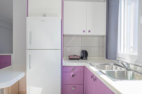 uma cozinha com armários cor-de-rosa e um lavatório em Lefkothea Apartments em Nikiana