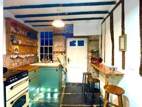 uma cozinha com um frigorífico verde e um balcão em Castle Buildings Cottage1 em Llanrhaeadr-ym-Mochnant