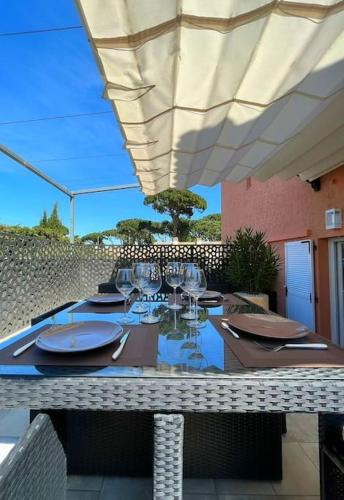 stół z talerzami i okularami siedzący pod parasolem w obiekcie Studio climatisé, terrasse, parking privé, 50m de la plage w Saint-Tropez