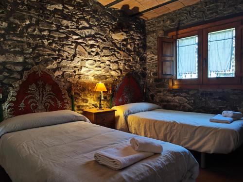 a bedroom with two beds and a stone wall at Allotjaments Cal Llarg in Molló