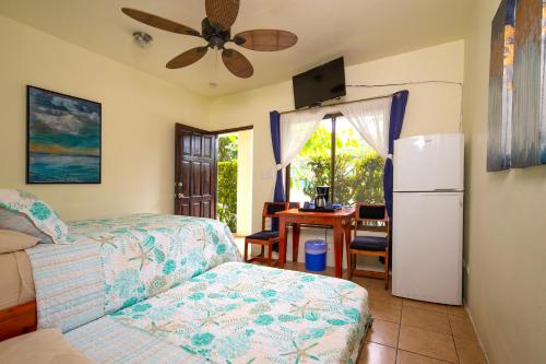 a room with a bed and a refrigerator and a table at Hotel Diversion Tropical in Brasilito
