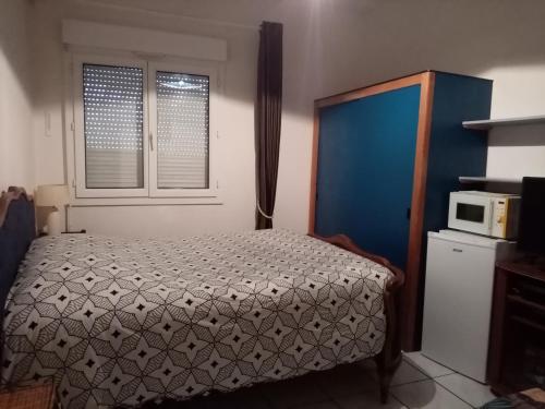 1 dormitorio con 1 cama y microondas en chambre meublée en Champigneulles