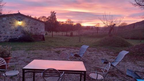 a table and chairs in a field at sunset at Molino della Tuoma in San Quirico dʼOrcia
