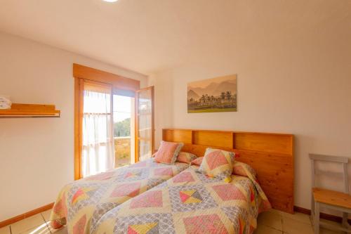 1 dormitorio con 1 cama con edredón y ventana en Cal Planell Casa Rural, en Vall-Llebrera