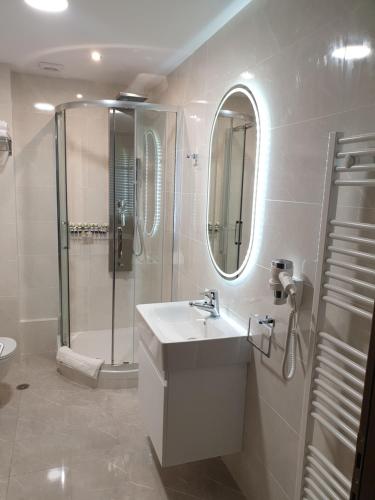 a white bathroom with a sink and a shower at Olive Deluxe Apartment in Karditsa