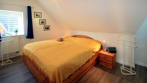 a bedroom with a large bed with a yellow bedspread at Gaestehaeuser-Heidehof-Wohnung-4 in Süderhöft