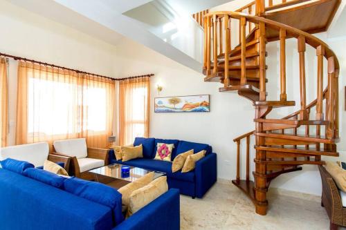 a living room with a blue couch and a wooden staircase at Ocean Views & Private Beach! Luxury 4BDR Getaway in Punta Cana