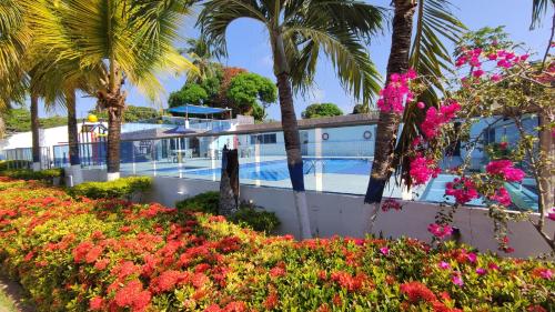 un complexe avec une piscine, des palmiers et des fleurs dans l'établissement Cabaña 5 Castillo Club House, à Coveñas