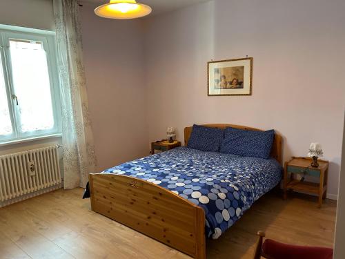 - une chambre avec un lit doté de draps bleus et une fenêtre dans l'établissement Appartamento Vanoi nel cuore verde del Trentino, à Canal San Bovo