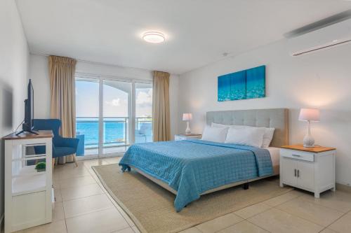 a bedroom with a bed and a view of the ocean at Sunset Beach Condo - Luxury 1BR Suite next to The Morgan Resort in Maho Reef