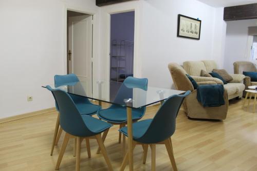 a dining room with a glass table and blue chairs at Al pie del Camarín con parking gratis in Jaén