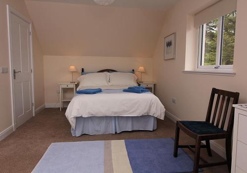 a bedroom with a bed and a chair and a window at Tigh Uisdean Bed and Breakfast in Achiltibuie