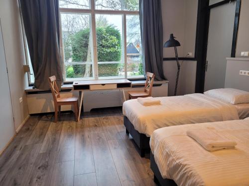 1 dormitorio con 2 camas, escritorio y ventana en L'appel Studio near Amsterdam, en Warder