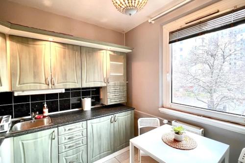 a kitchen with a sink and a table and a window at Pille Apartman in Szeged