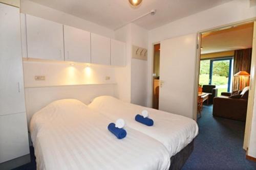 een hotelkamer met een bed met blauwe kussens erop bij Heerlijk App APHRODITE - beg grond met TERRAS, eigen KEUKEN, Incl Verwarmd Hotel-ZWEMBAD, nabij Strand en Vuurtoren in Hollum