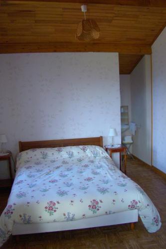 una camera da letto con un letto con copriletto floreale di CHAMBRES D'HOTES LES GRAVES a Saint-Pierre-Lafeuille