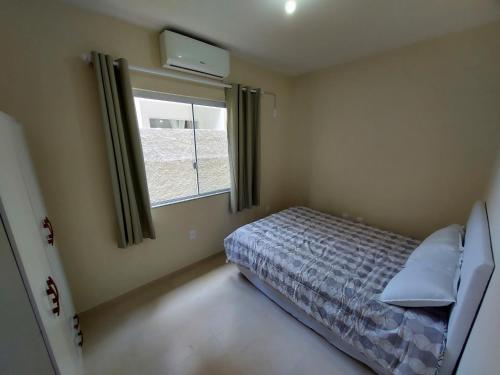 a bedroom with a bed and a window at Apartamento Descubra Palhoça - Pinheira in Palhoça