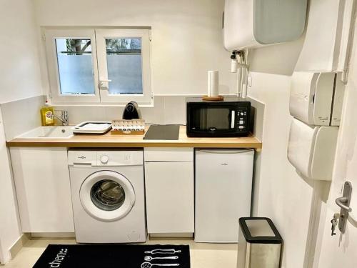 eine Küche mit einer Waschmaschine und einer Mikrowelle in der Unterkunft Entre Paris, Versailles et La Défense in Chaville