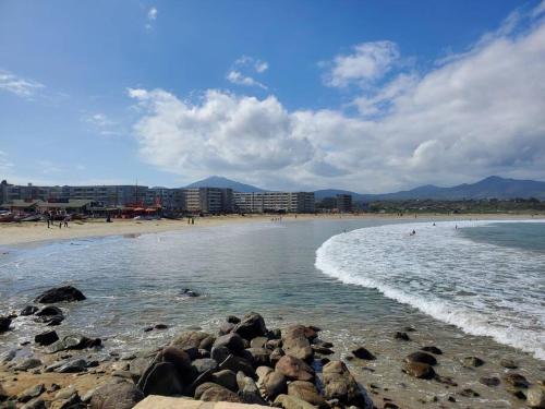 a beach with rocks in the water and buildings at Depto frente al mar en Los Molles in Los Molles