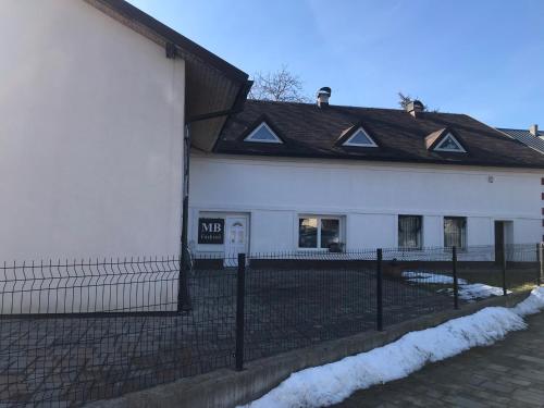 a white building with a black roof and a fence at Aparmánový byt v centre Banskej Bystrice & free parking in Banská Bystrica