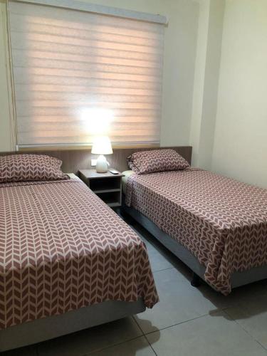 a bedroom with two beds and a window with a lamp at Garzota Garden PB in Guayaquil