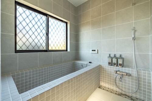 a bathroom with a bath tub and a window at 思い出になる九十九里の古民家ドマノマ ハンモック バーベキュー in Kujukuri