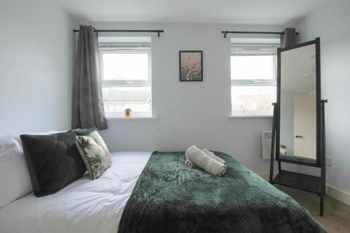 Schlafzimmer mit einem Bett, einem Spiegel und Fenstern in der Unterkunft Stayright Stylish Cardiff Bay 2 Bed Apartment- Private Parking & 10 mins to Bay & City in Cardiff