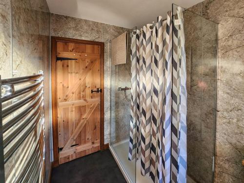 a bathroom with a wooden door and a shower at East Lodge in Kingholm Quay