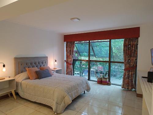 1 dormitorio con cama y ventana grande en MENDOZA Suites 8 en Mendoza