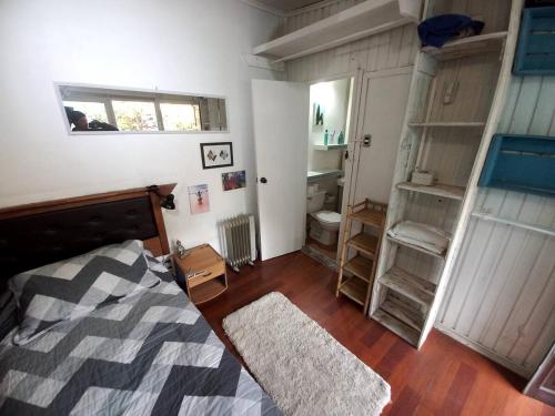 a bedroom with a bed and a bathroom with shelves at Pieza independiente en casa compartida en Vitacura cn bici y piscina in Santiago