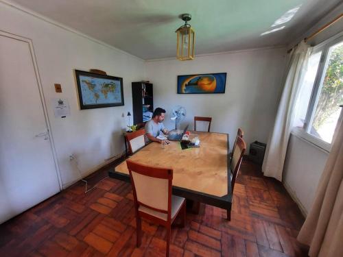 een man aan een houten tafel in een kamer bij Pieza independiente en casa compartida en Vitacura cn bici y piscina in Santiago