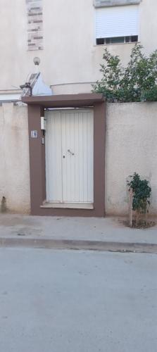 a garage with a white door on the side of a building at Studio, Cité la GAZELLE ,pas Jafar, quartier calme 10 min de l'aéroport près du Technopark in Jafar