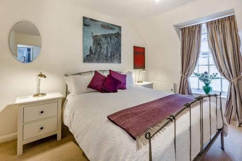 a bedroom with a bed with purple pillows and a mirror at 138E Old Star & Garter Mews in Ludlow